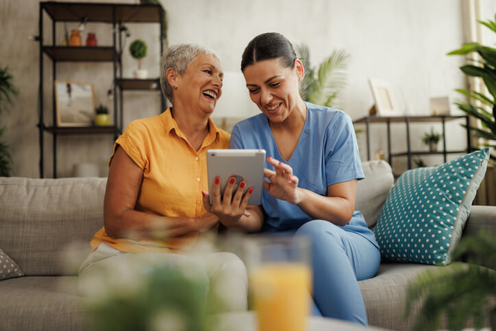 Caregiver assisting senior with health technology.